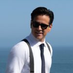 Sugar Season 2 promotional image showing a detective in sunglasses standing near the ocean.
