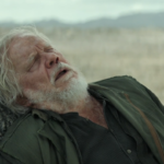Bernard Holland collapses against a tree after being sent outside to clean without a suit in Silo Season 3 Episode 9.