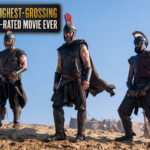 Three armored warriors from The Odyssey stand in a desert beneath a graphic declaring it the highest-grossing R-rated movie ever.