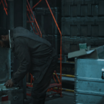 Sheriff Billings searches storage containers in Critical Supply during Silo Season 3.