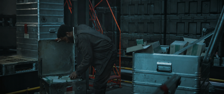 Sheriff Billings searches storage containers in Critical Supply during Silo Season 3.