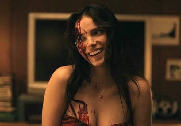 Inde Navarrette as Nikki smiling with blood on her face in Obsession
