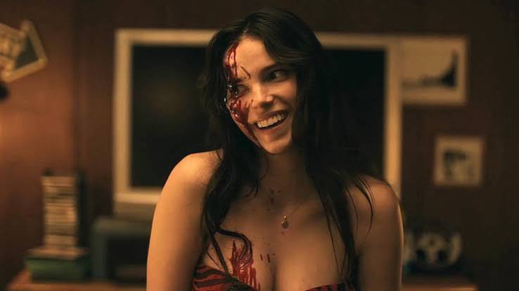 Inde Navarrette as Nikki smiling with blood on her face in Obsession